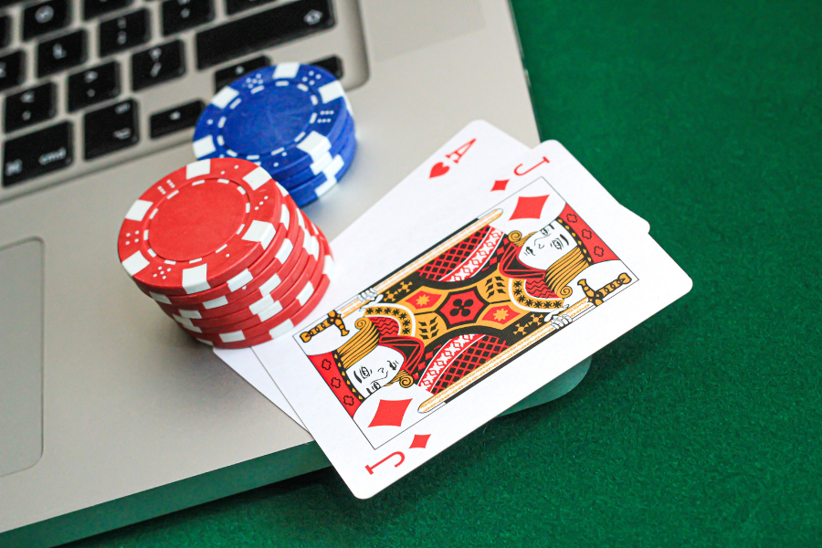 A laptop with a crypto casino open, poker coins and some card on a side 