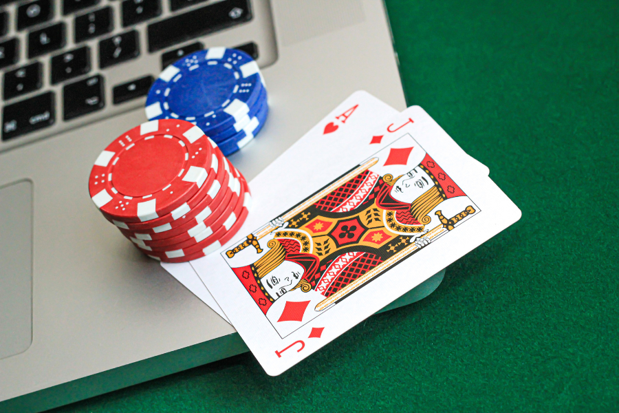 A laptop with a crypto casino open, poker coins and some card on a side