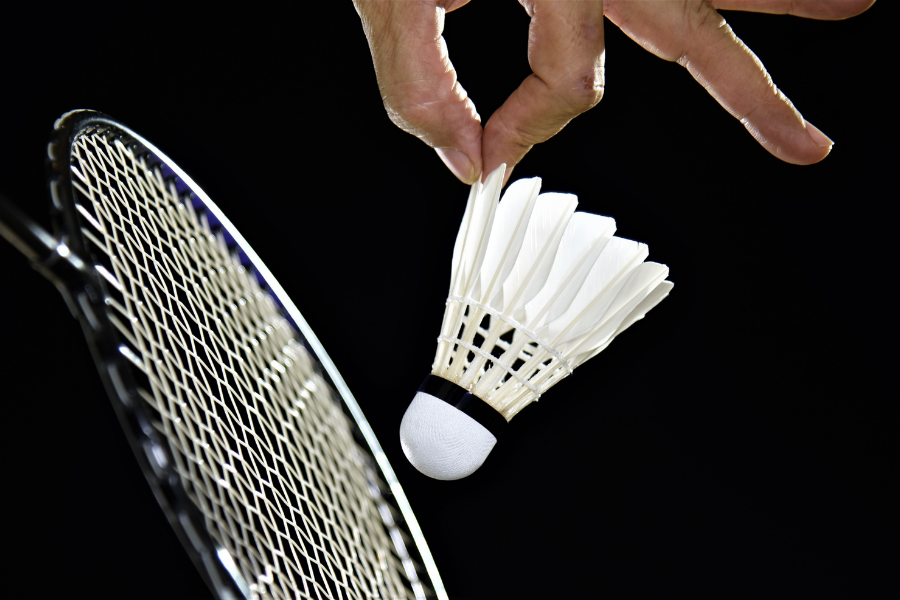 a person hold a shuttlecock with a badminton racket